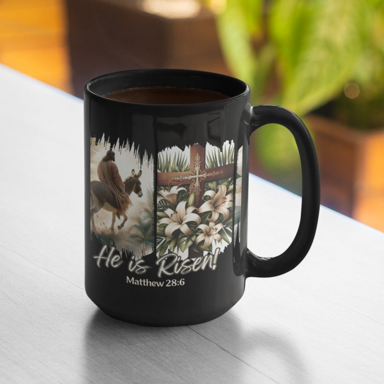 Easter Black 15oz coffee mug with a depiction of Jesus riding a donkey, a detailed cross adorned with lilies, and elegant floral touches, all set against a dramatic black brushstroke backdrop. Also features the words He is Risen! and the Bible verse Matthew 28:6 at the bottom of the mug.