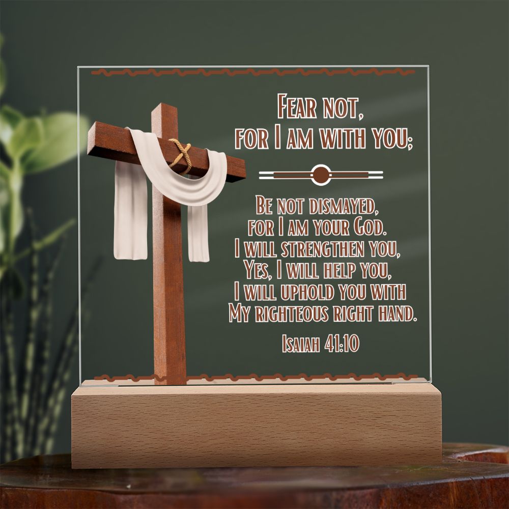 Image is of a clear acrylic square that features Bible verse Isaiah 41:10. Fear Not For I Am With You... Also has a 3d image of a brown cross with a beige scarf draped over it. The acrylic square sits in a wooden base.