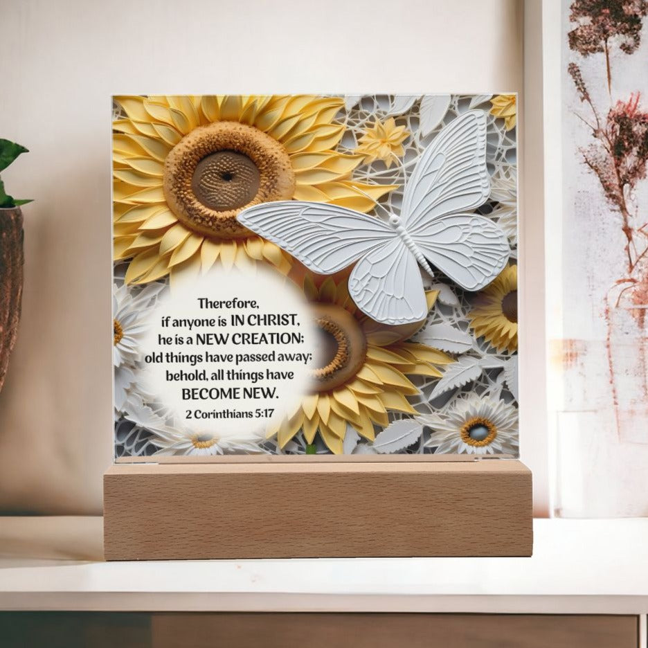 Acrylic Bible verse decorative plaque features a captivating image of a beautiful white butterfly along with Bible Verse 2 Corinthians 5:17. The butterfly as well as the flowers surrounding it, appears to be in 3D.
