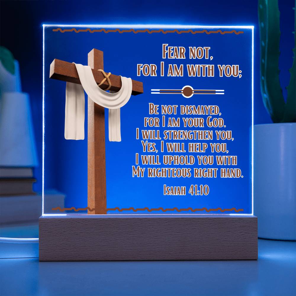 Image is of a clear acrylic square that is displayed in the LED color blue and features Bible verse Isaiah 41:10. Fear Not For I Am With You... Also has a 3d image of a brown cross with a beige scarf draped over it. The acrylic square sits in a wooden base.