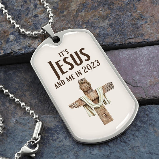 It's Jesus and Me In 2023 Christian dog tag necklace. Cream color with cross made of wood and a crown of thorns on top of it. Necklace is resting on flat rocks.