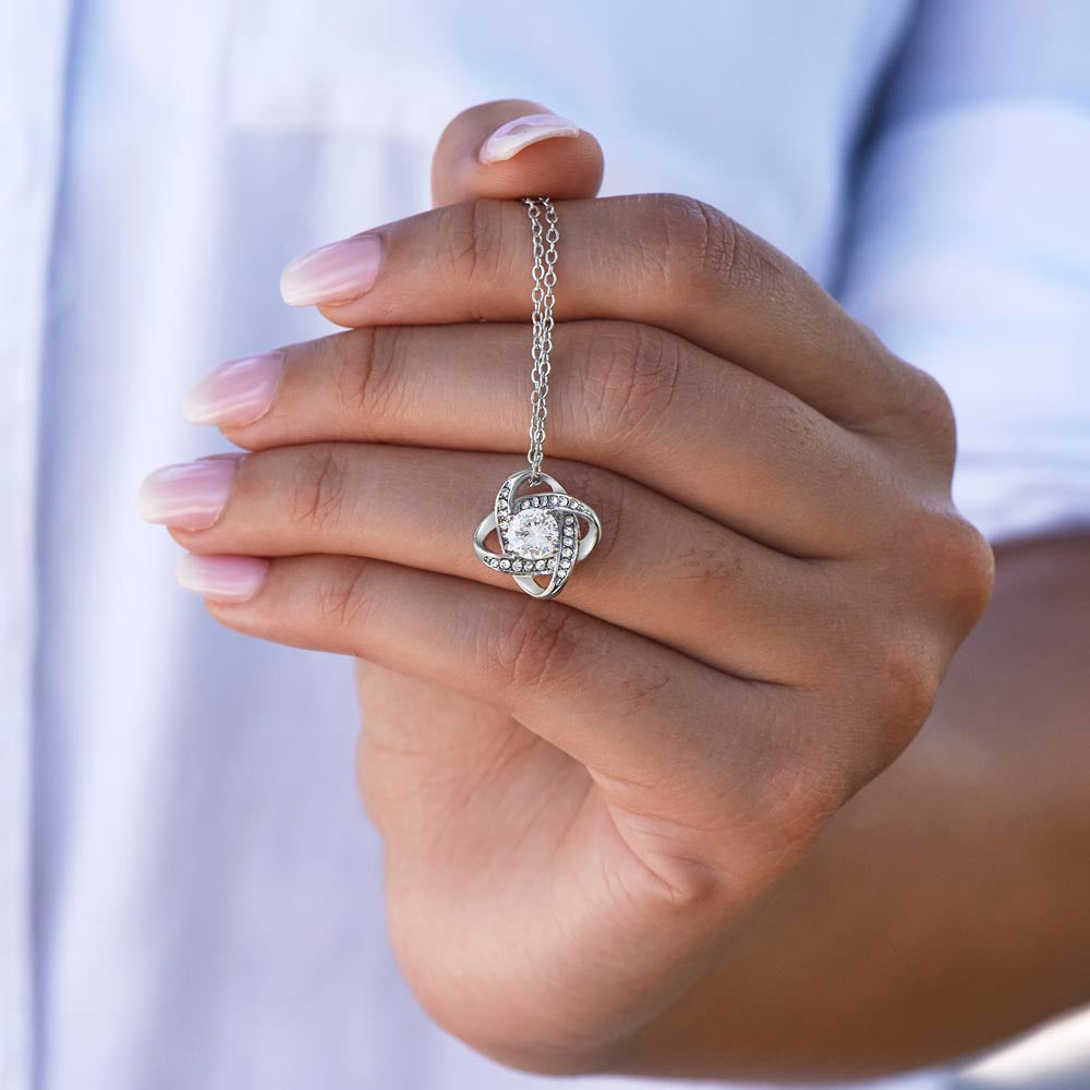 Love Knot necklace being held in front of a hand.