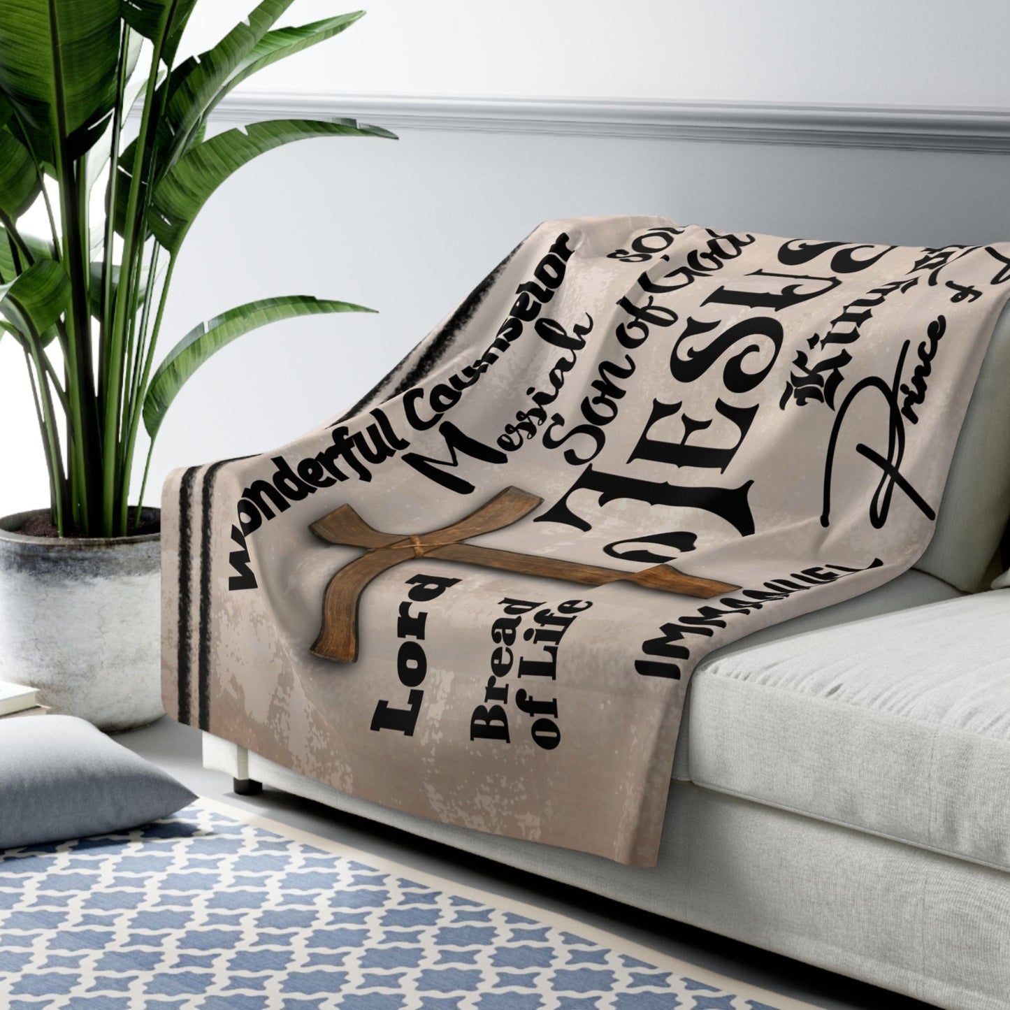 The Names of Jesus Throw is tan with black text throughout the blanket. It features a brown cross and  the names of Jesus in several different font types. Some names included are: Prince of Peace, King of Kings, Messiah, and so forth.