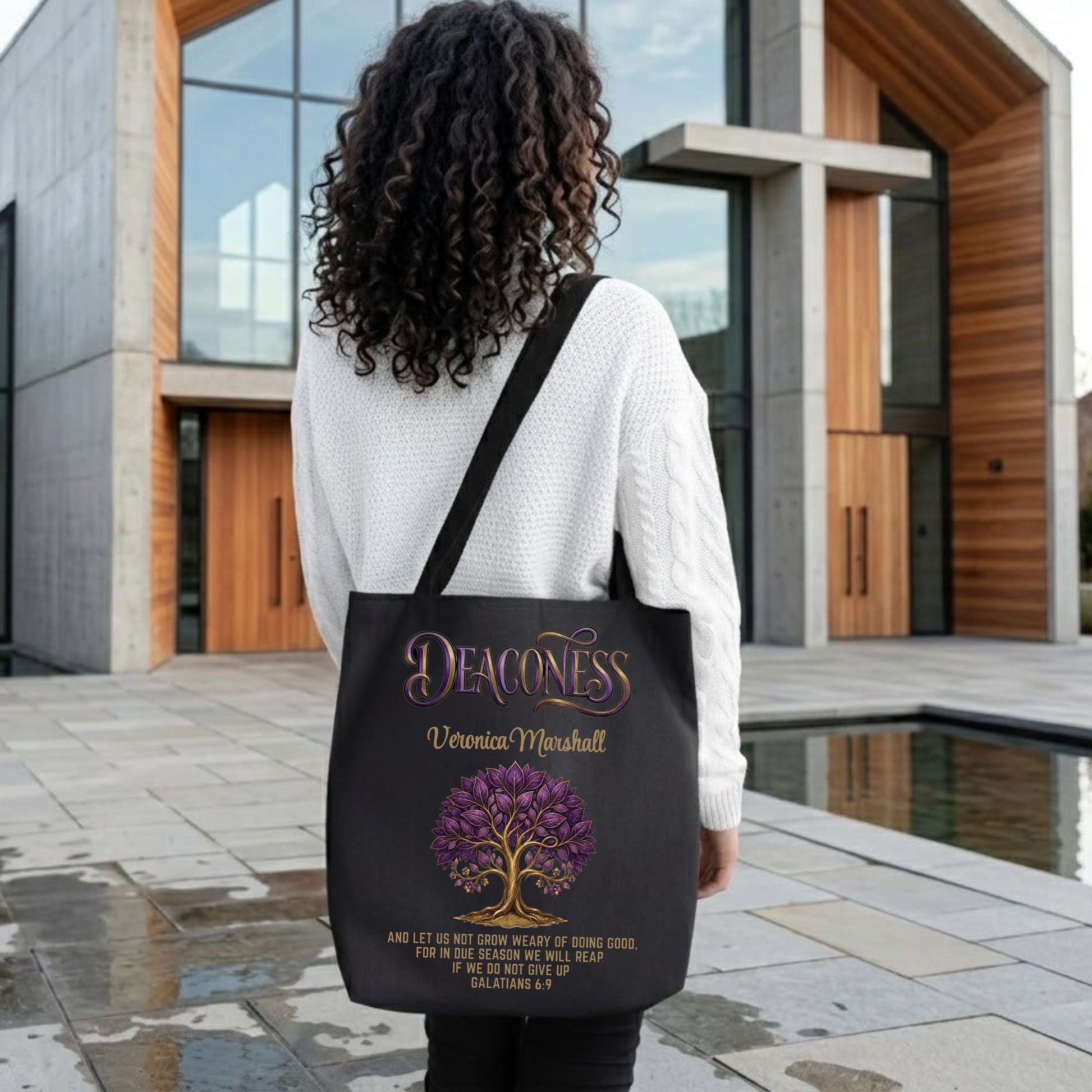 Woman holding a black tote bag with the text 'Deaconess," and Bible scripture design in front of a modern church building.