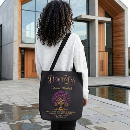 Woman holding a black tote bag with the text 'Deaconess," and Bible scripture design in front of a modern church building.