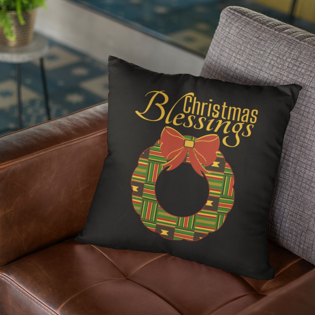Black pillow with the words Christmas Blessings above a Kente designed Christmas Wreath with red bow on the wreath.