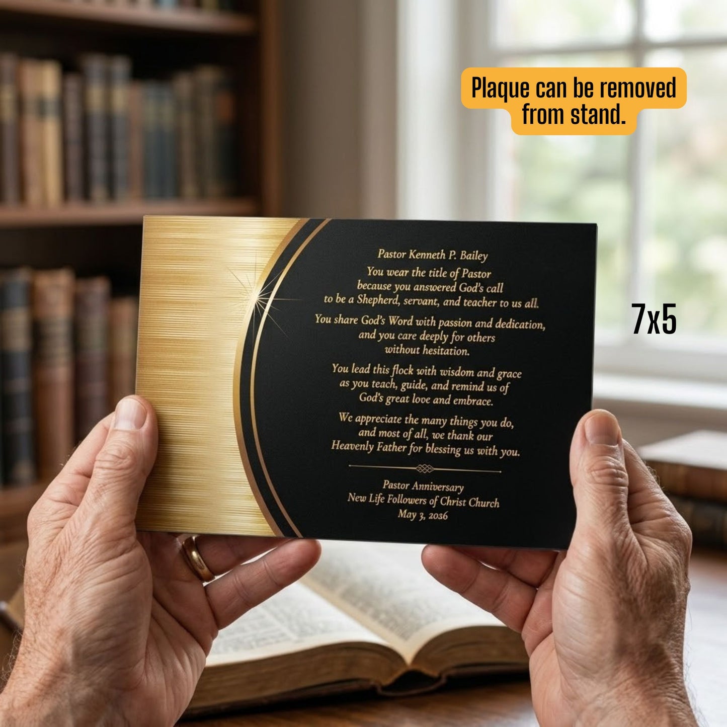 Person holding a pastor appreciation plaque with gold and black on an acrylic surface. A bookshelf is in the background. 