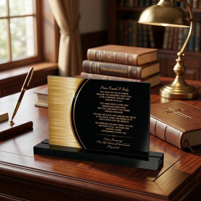 Pastor appreciation decorative plaque with printed text on a black and gold background and a black acrylic stand. The plaque is sitting on a wooden desk with books and a lamp in the background.