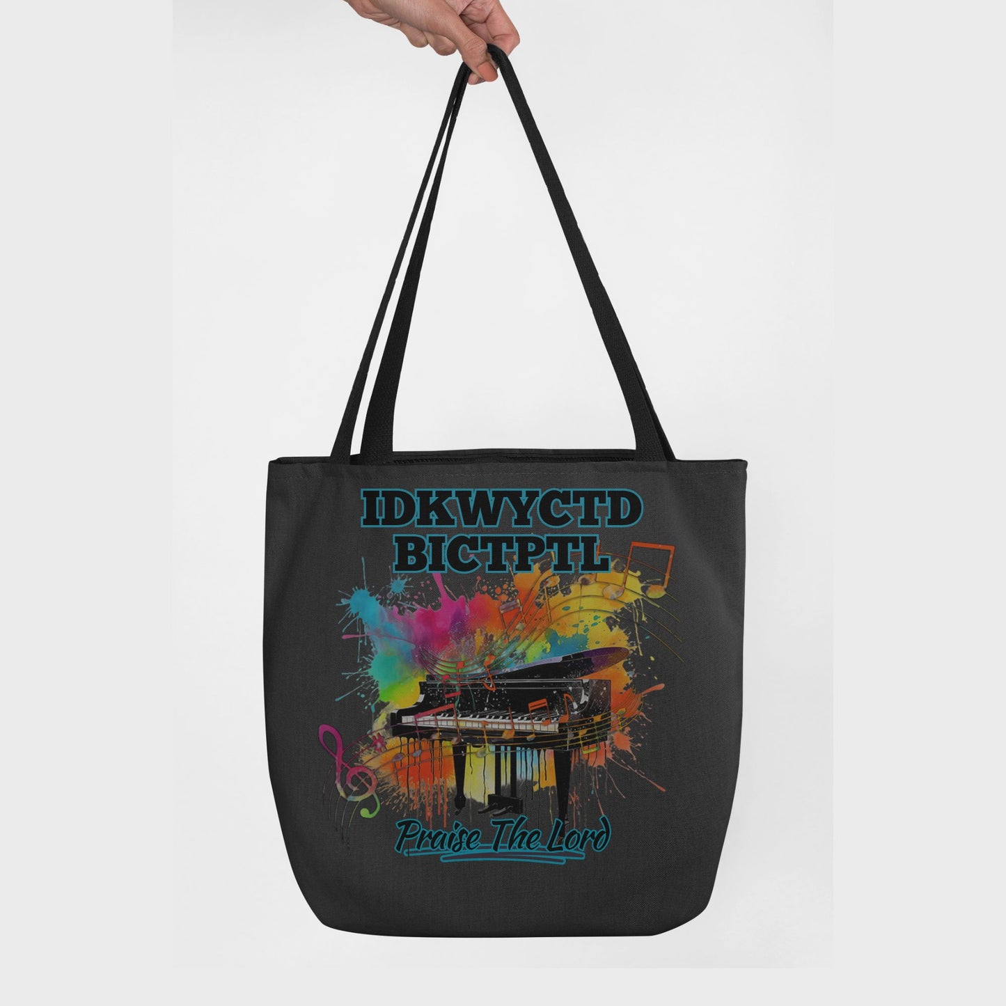 Black tote bag with a colorful piano design and text KWYCTDBICTPTL - Praise the Lord on a white background.