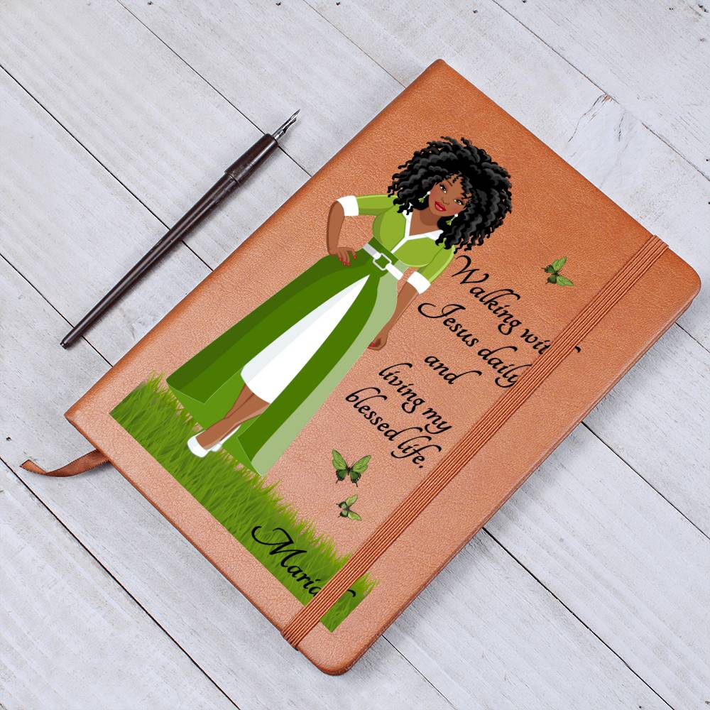 African American Woman dressed in green and white art with Christian quote on the front cover of a light brown vegan writing journal. Christian quote says, "Walking With Jesus daily and living my blessed life." Also has images of green butterflies and a place at the bottom for personalizing with a name.