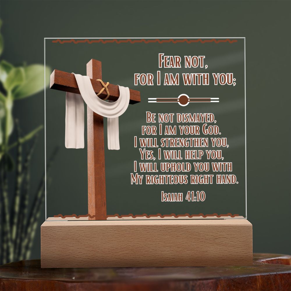 Image is of a clear acrylic square that features Bible verse Isaiah 41:10.  Fear Not For I Am With You...  Also  has a 3d image of a brown cross with a beige scarf draped over it. The acrylic square sits in a wooden base.