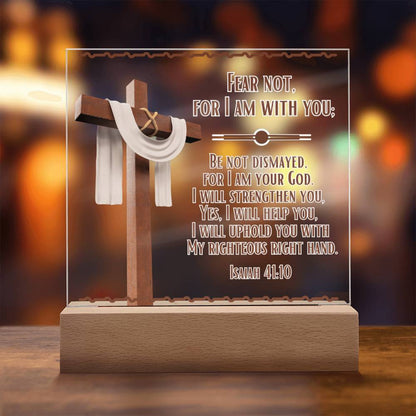 Image is of a clear acrylic square plaque and features Bible verse Isaiah 41:10.  Fear Not For I Am With You...  Also  has a 3d image of a brown cross with a beige scarf draped over it. The acrylic square sits in a wooden base.