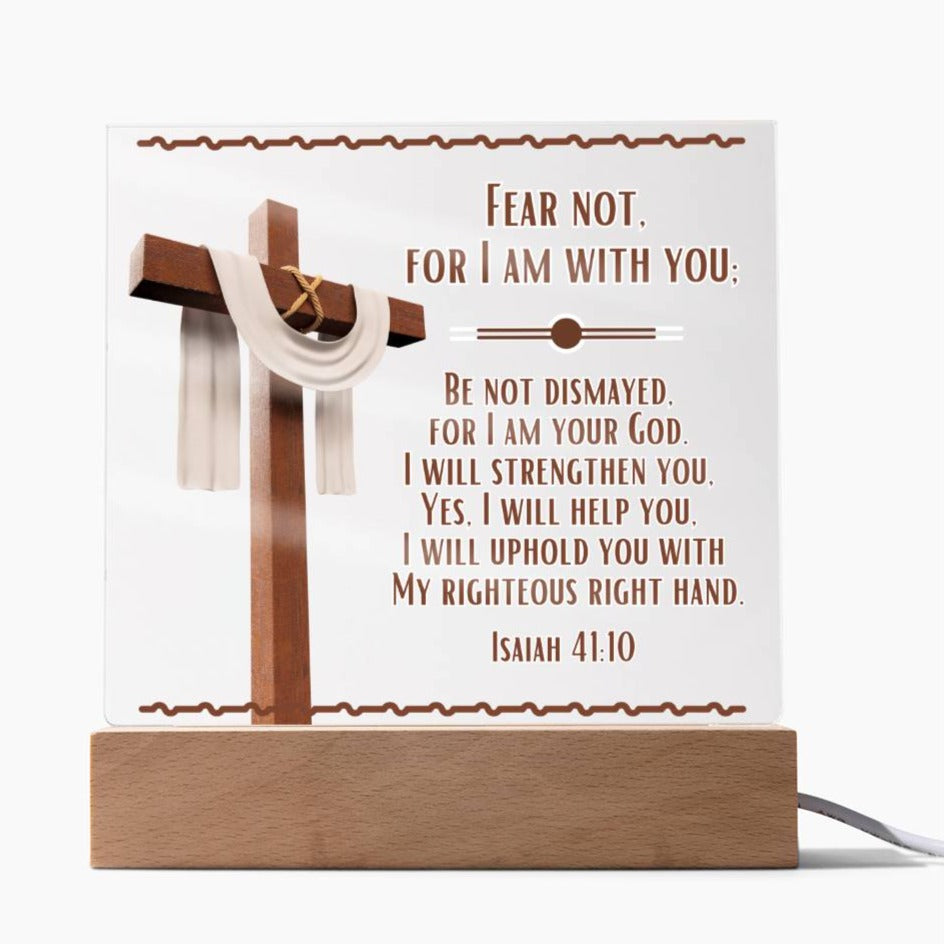 Image is of a clear acrylic square that is displayed in the LED lights and features Bible verse Isaiah 41:10.  Fear Not For I Am With You...  Also  has a 3d image of a brown cross with a beige scarf draped over it. The acrylic square sits in a wooden base.