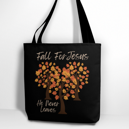 Fall For Jesus He Never Leaves Christian Quote Tote Bag. Features three trees with autumn leaves positioned to form a heart. Tote is all black polyester. Print is on both sides of bag.
