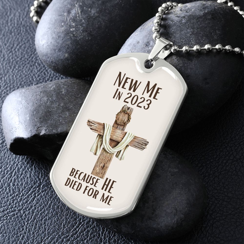 New Me In 2023 Because He Died For Me silver Dog Tag Necklace. Features a wooden cross with a crown of thorns on it with a cream background. Displayed on rocks.