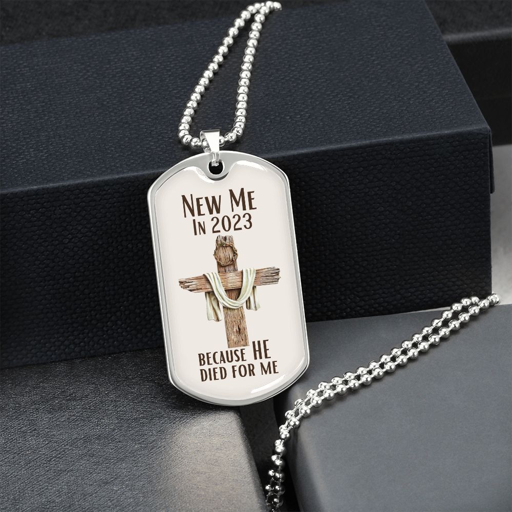 New Me In 2023 Because He Died For Me silver Dog Tag Necklace. Features a wooden cross with a crown of thorns on it with a cream background. Displayed in front of box.