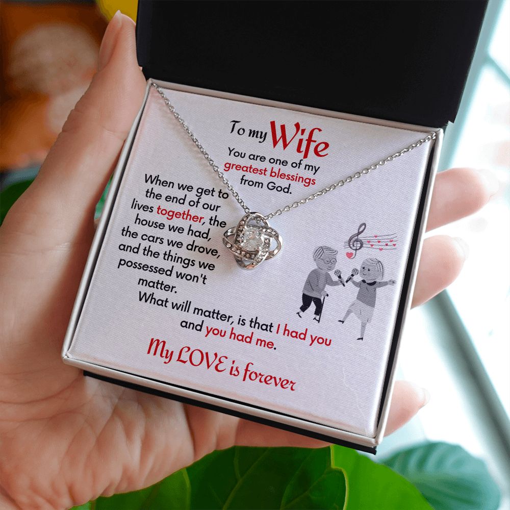 To Wife Love Knot necklace with jewelry message card. Card features special message to wife with an elderly man and woman singing together. Card is white background. Shown being held in a hand.