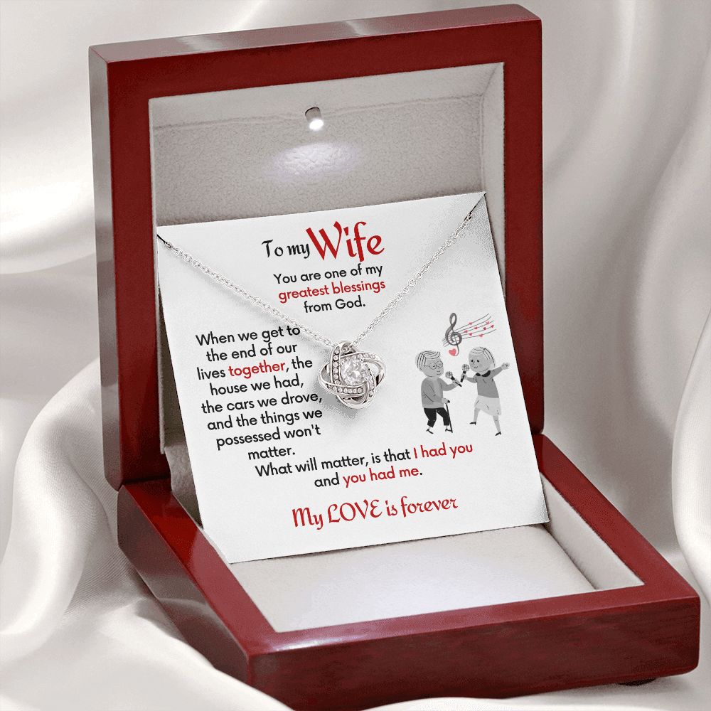 To Wife Love Knot necklace with jewelry message card. Card features special message to wife with an elderly man and woman singing together. Card is white background. In mahogany box with LED light and box open with card standing up inside.
